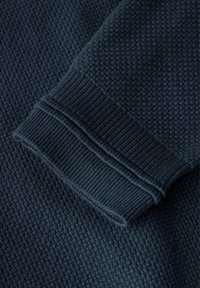 Dunkelblauer Pullover mit detailliertem Waffelstrickmuster, geripptem Bündchen und glatter Stoffoberfläche.