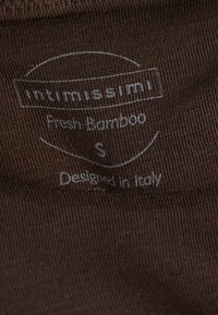 Bruin textiel met een ribbelstructuur met een wit label waarop staat "Intimissimi Fresh Bamboo S Ontworpen in Italië."
