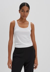 Witte mouwloze tanktop van katoen, met een ronde hals en een soepele textuur. Gepaard met zwarte, losse broek.