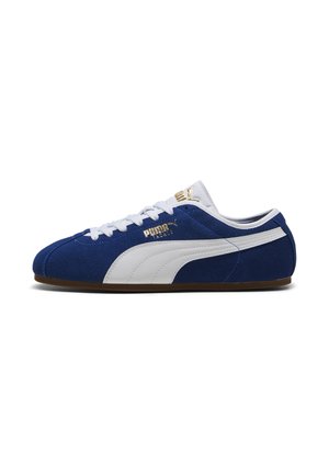 Sneaker Puma in camoscio blu con striscia bianca, lacci bianchi e logo Puma dorato sul lato e sulla linguetta, vista di profilo.