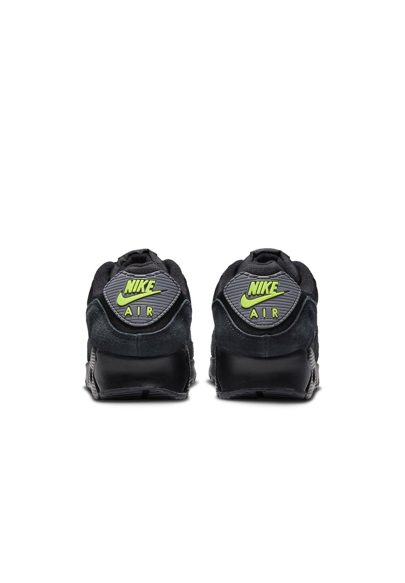 Zapatillas Nike de ante negro y malla con un respaldo texturizado, que presentan un logo verde brillante y suelas completamente negras. Vista trasera de los zapatos.