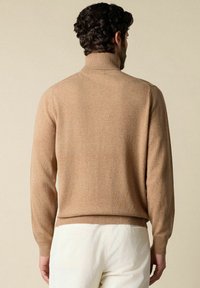 Beige gestrickter Pullover mit hohem Kragen, enganliegenden Bündchen und texturiertem Finish. Weicher Stoff, schlichtes Design und klassische Silhouette.