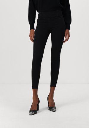 Leggings noirs au design épuré et ajusté, avec une texture lisse. Portés avec des chaussures à talons hauts noires avec un détail de bout brillant.