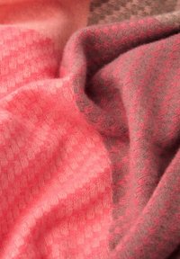 Vævet plaid i bløde lyserøde og grå nuancer, med et tekstureret ternet mønster og en subtil blanding af farver og blødhed.