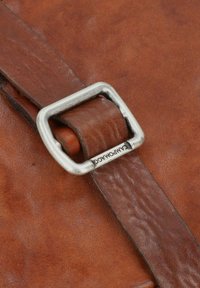 Braune Ledertasche mit strukturiertem Finish, ausgestattet mit einer silbernen rechteckigen Schnalle und dem Markennamen am Riemen für einen sicheren Verschluss.