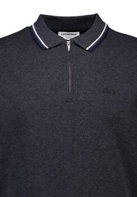 Marinblå polo-shirt i texturerat tyg, med dragkedja i halsen, kontrasterande vit och marinblå randig krage samt subtilt varumärkessegment.
