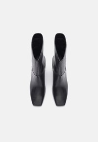 Czarne skórzane botki za kostkę z prostokątnym noskiem i gładką powierzchnią, charakteryzujące się eleganckim designem i minimalnym przeszyciem, z widocznym wnętrzem.