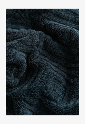 DunkelblauesFrotteehandtuchgewebe mit einem strukturierten Muster. Weiche, plüschige Fasern verleihen ein gemütliches Aussehen und ein angenehmes Gefühl.