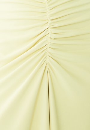 Heled kollane kangas, mille keskel on kokku kogutud detailid, siledat tekstuuri ja vertikaalsed voldid.