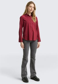 Roter gemusterter Hemd mit langen Ärmeln, kombiniert mit grauen Schlagjeans und schwarzen Schuhen. Glatte Stofftextur, klassisches Design.
