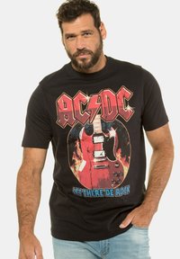 Camiseta negra con un diseño gráfico de una guitarra eléctrica roja rodeada de llamas y el texto "AC/DC Let There Be Rock" en colores llamativos.