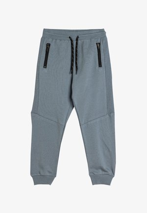 Grijze joggerbroeken met ribbelstructuur, elastische tailleband en verstelbaar zwart trekkoord. Voorzien van twee met rits afgesloten zakken aan de voorkant.