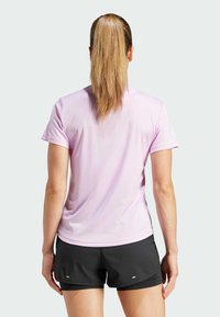 Camiseta atlética de manga corta en color púrpura claro, hecha de un tejido suave y transpirable, combinada con pantalones cortos negros que presentan un pequeño detalle reflectante.