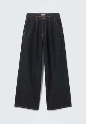 Dunkelblaue, weite Jeans mit Vorderfalten, schrägen Taschen, Gürtelschlaufen und einem Knopfverschluss am Taillenbund, beschriftet mit "WEEKDAY."