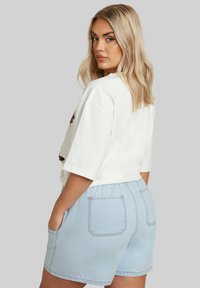 Vaaleanharmaa t-paita, jossa on ylisuuri istuvuus ja lyhyet hihat, yhdistettynä vaaleansinihin shortseihin, joissa on rento vyötärö ja takataskut.