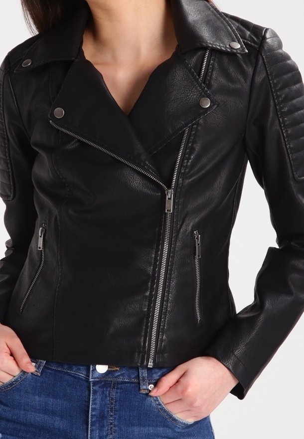 Kvinna som bär en svart läderjacka med dragkedja, diagonalt fram med kviltade axeldetaljer, i kombination med blå jeans.