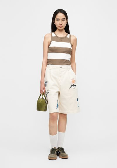 Débardeur rayé marron et blanc, short beige avec broderie florale, sac à main vert, chaussettes blanches et baskets olive. Design simple, coupe décontractée.