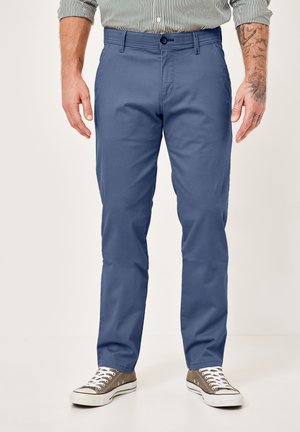 Blue cotton trousers with a flat front, belt loops, and a button closure. Styled with a slim fit, paired with gray sneakers.