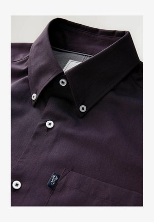 Tume lilla nööriga särk struktuurse kraega, valged nööbid, rinna tasku ja väike logo silt tasku lähedal. Tekstuuriga kangas.