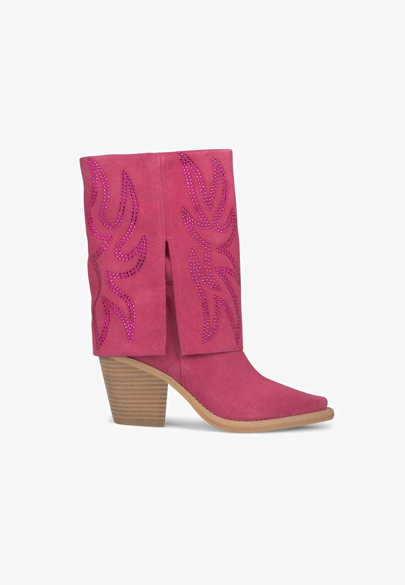 Bottes de cowboy en daim rose avec un bout pointu, un talon block de hauteur intermédiaire, et des découpes ornées de strass.