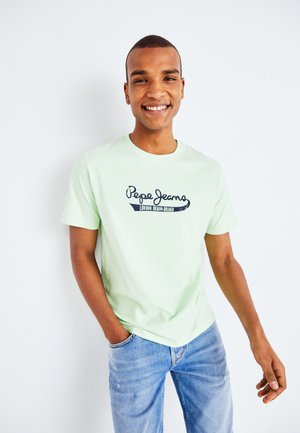 T-shirt en coton vert clair à col rond, affichant un imprimé de logo bleu marine "Pepe Jeans" et un jean bleu denim à coupe décontractée.