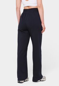Navy cotton blend sweatpants with an elasticated waistband, relaxed fit, and straight leg design. Pairing with gray and black sneakers.