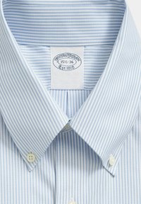 Hellblau-weiß gestreiftes Hemd mit button-down Kragen, aus glattem Stoff gefertigt und mit zwei Knöpfen am Kragen ausgestattet.