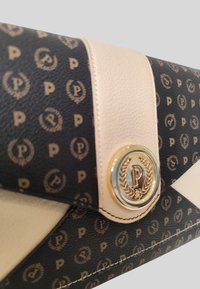 Borsa a pochette nera e beige realizzata in pelle testurizzata con motivo a logo dorato, caratterizzata da un'emblema circolare dorato e accenti di design diagonali.