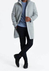 Abrigo gris claro con capucha, suéter azul de punto acanalado, pantalones de cuadros azul marino y botines de ante oscuro, mostrando varias texturas y colores.