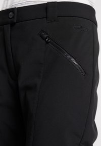 Schwarze Softshell-Hosen mit glatter Textur, ausgestattet mit einer seitlichen Reißverschlusstasche und einem dezenten Logo. Maßgeschneiderte Passform und praktisches Design.