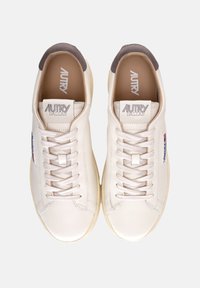 Sneaker bianche in pelle con accenti crema, punta rotonda, lacci piatti e un tassello di tacco marrone. Logo "AUTRY DALLAS" sulla linguetta.