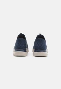 Bottines navy bleues à enfiler avec un dessus texturé, des accents lisses et une semelle extérieure flexible de couleur claire ; dotées de deux languettes à l'arrière.