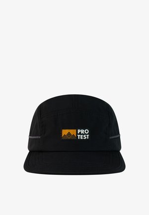 Zwarte vijf-panelen pet met een vlakke klep, met een geel-zwarte patch met de tekst "PRO TEST" en een bergafbeelding.