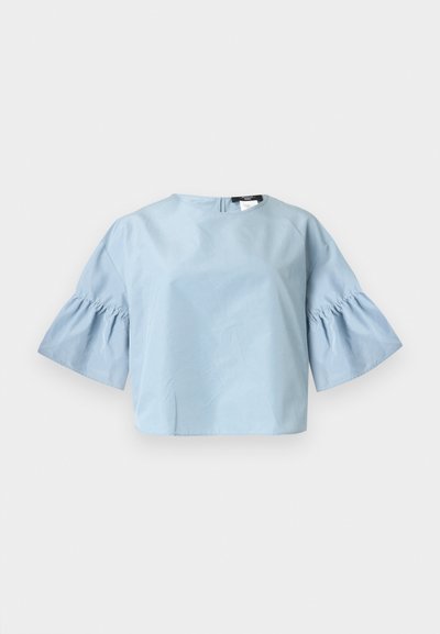 Blouse bleu clair à manches courtes avec manches larges et volantées et un col rond, présentée sur un fond blanc uni.