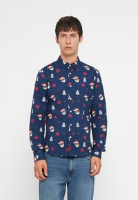 Camisa de manga larga azul con un patrón festivo de caras de Santa, copos de nieve y árboles. Hecha de una tela con una textura suave y cierre de botones.