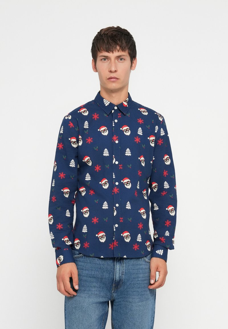 Camisa de manga larga azul con un patrón festivo de caras de Santa, copos de nieve y árboles. Hecha de una tela con una textura suave y cierre de botones.