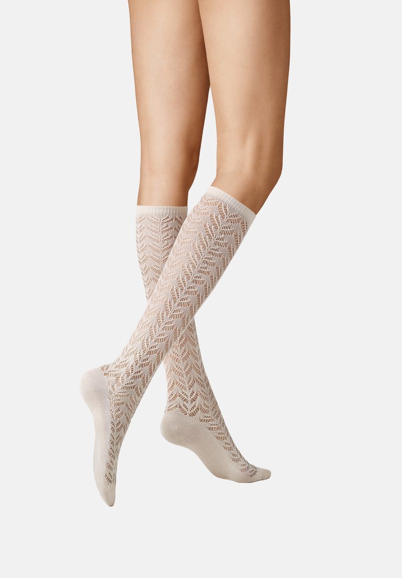 Kniestrümpfe in hellbeige mit einem strukturierten, offenen Strickmuster, das ein Blättermuster zeigt, und mit gerippten Bündchen sowie verstärkten Fersen versehen.