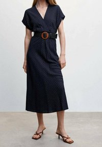 Navy raidallinen kietaisumekko lyhyillä hihoilla, jossa on leveä musta vyö puu-soljella. Keskivartaloa hivelevä pituus, pehmeä kangas, minimaalinen tekstuuri.