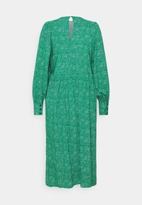 Longue robe verte à petit motif de pois blancs, manches longues bouffantes avec poignets boutonnés, et une découpe en forme de trou de serrure au niveau de l'encolure.