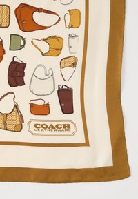 Silk scarf featuring an illustration of various handbag designs in brown, orange, green, and yellow on a cream background with a brown border.