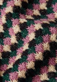 Knit textile featuring a green, black, cream, and pink geometric pattern with a textured, fuzzy appearance and metallic thread accents.