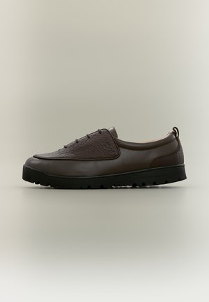 Chaussure décontractée en cuir marron foncé avec panneau supérieur texturé, lacets à l'avant et semelle en caoutchouc noir robuste sur fond neutre.