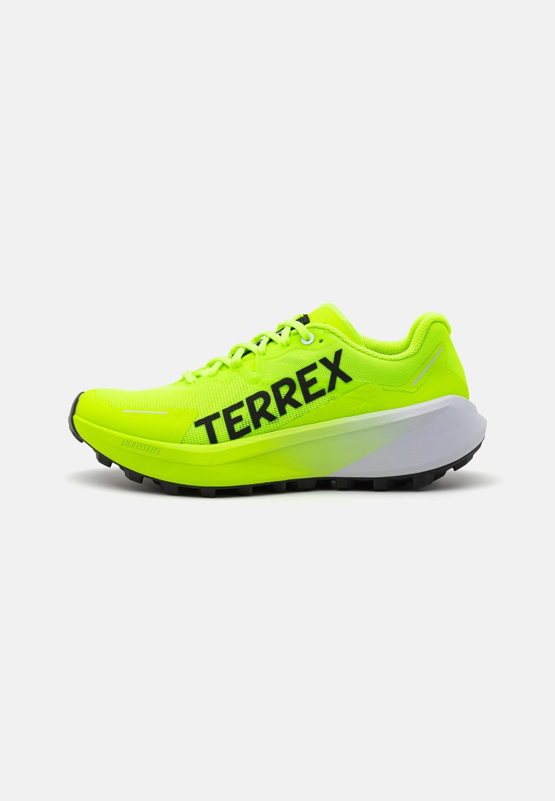 Svijetlo neonske žute tenisice za trčanje s prozračnim mrežastim gornjim dijelom, crnim logotipom "TERREX", i udobnim bijelim srednjim potplatom. Teksturirani gumeni potplat.