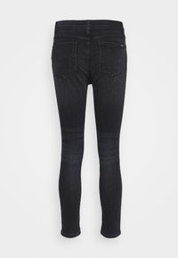 Jeans skinny negros con cinco bolsillos, trabillas para cinturón y una cinturilla sólida. Presentan una textura suave y mínimas decoloraciones.