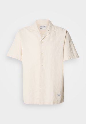Short-sleeve, light beige shirt made of textured fabric with a pointed collar, featuring a button front and a small label on the hem.
