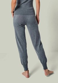 Graue gestrickte Jogginghosen mit schmal zulaufenden Knöchelbündchen und einer weichen Textur, kombiniert mit einem passenden grauen Rippoberteil.