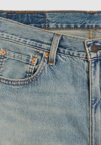 Primer plano de unos vaqueros de mezclilla azul claro que muestran el bolsillo delantero, la presilla del cinturón, el botón y los detalles de costura en color naranja.