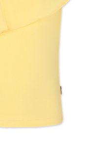 Top corto giallo a maniche corte che combina una texture a coste e una sovrapposizione liscia. Presenta un orlo arrotondato e un piccolo tag del marchio sul lato.