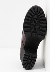 Botte en cuir marron avec une texture crocodile, dotée d'une semelle en caoutchouc noir avec un motif de semelle pour une adhérence optimale.