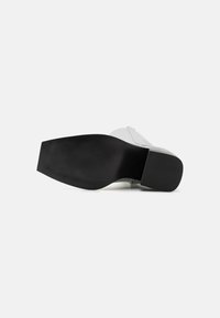 Semelle en caoutchouc noir avec une texture antidérapante, attachée à une partie supérieure gris clair en matériau lisse. Conçu pour le confort et la durabilité.